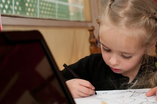 Little cute girl in black top is drawing