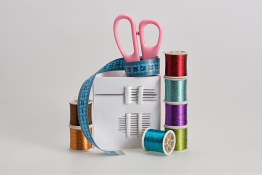 Coils with color strings of various color, sewing needles, scissors and sartorial centimeter