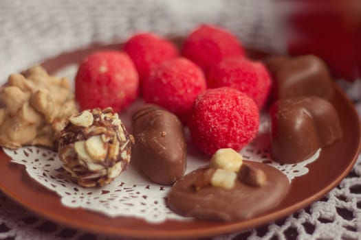 Set of chocolate candies, on plate, on wooden background