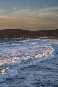 ocean shore of los angeles with wave breaking at sunset