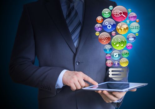 Businessman in a suit holding a tablet in his hands. Above the screen tablet application icons in the form of light bulb