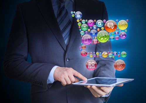 Businessman in a suit holding a tablet in his hands. Above the screen tablet application icons in the form of trolley