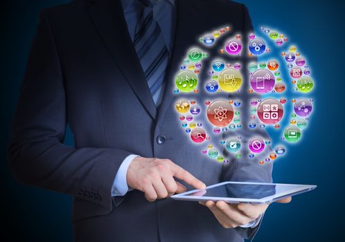 Businessman in a suit holding a tablet in his hands. Above the screen tablet application icons in the form of earth globe