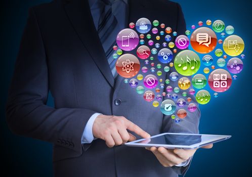Businessman in a suit holding a tablet in his hands. Above the screen tablet application icons in the form of heart