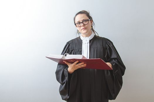 thirty something brunette woman wearing a canadian lawyer toga reading a red criminal law book