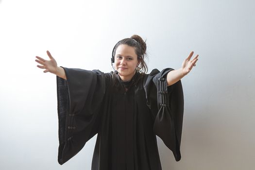 thirty something brunette woman wearing a preacher's toga opening her arm to the lord