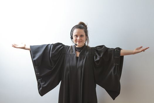 thirty something brunette woman wearing a preacher's toga opening her arm stretched as a cross