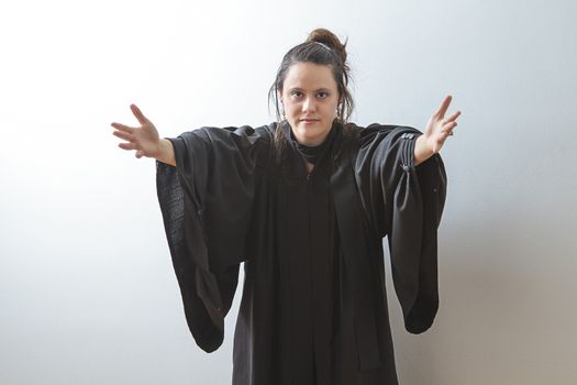 thirty something brunette woman wearing a preacher's toga with her arm streched out in front of her