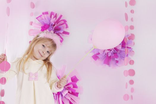 Happy little girl at pink decorated birthday party with balloon