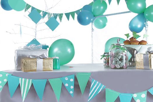 Blue and green colored birthday party table with sweets and decorations