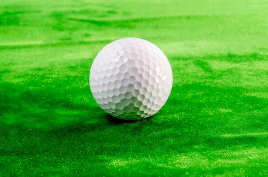 Close up of a golf ball on the green. Shallow depth of field.