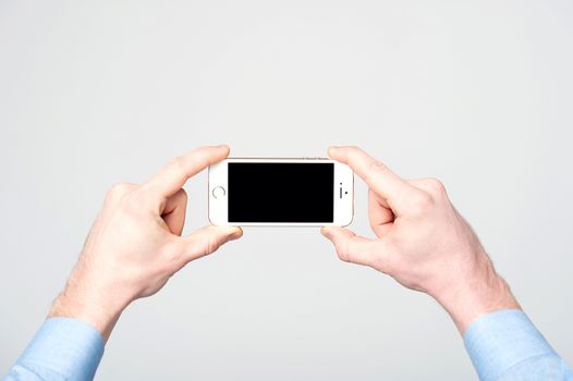Man hands holding new cellphone, over grey background