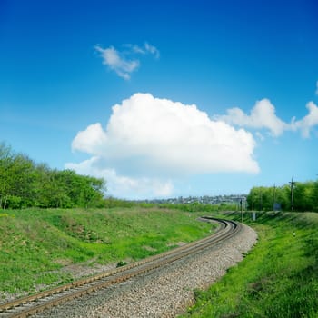 railroad in green landscape and clouds over it