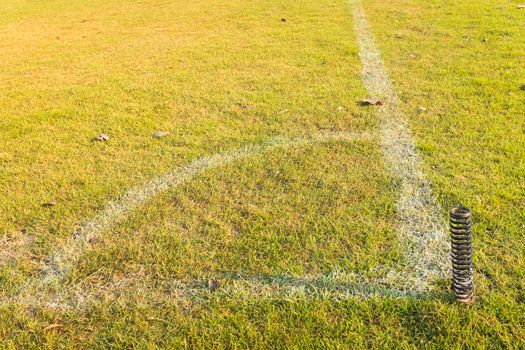 green grass corner of football or soccer field with white line and plugged flags