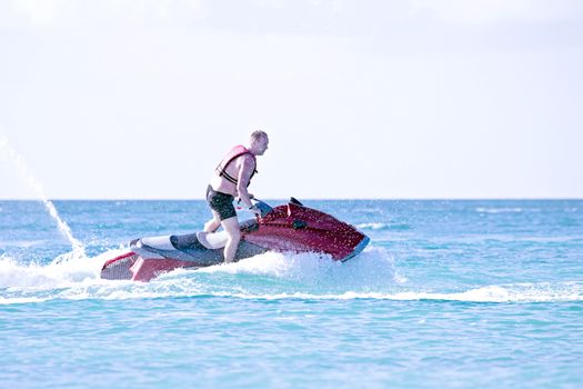 Young guy cruising in the caribbean sea on a jet ski