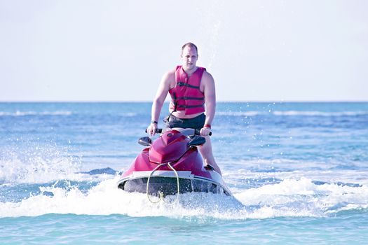 Young guy cruising in the caribbean sea on a jet ski
