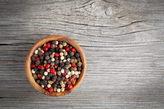 Colored Pepper in the wooden bowl, on wooden board