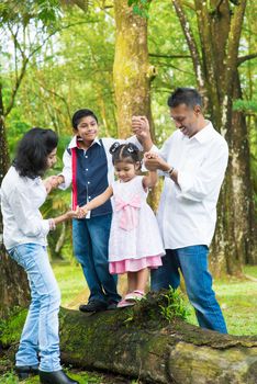 Happy Indian family at outdoor. Candid portrait of parents and children having fun at garden park. Exploring nature, leisure lifestyle.