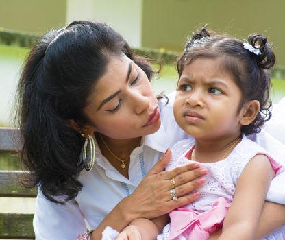 Indian family outdoor. Modern mother is comforting her crying daughter.