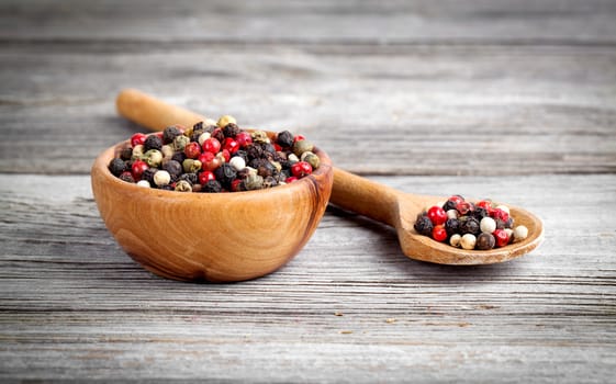Colored Pepper in the wooden bowl, on wooden board