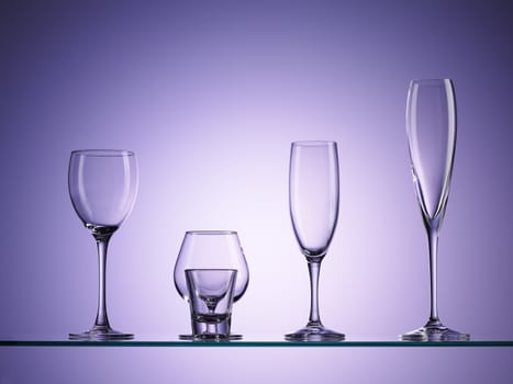 five empty wine glasses over purple background