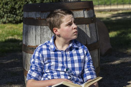 Young boy reading a book in the woods with shallow depth of field and copy space