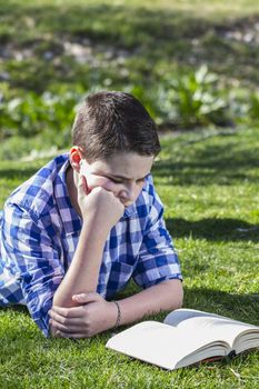 Young boy reading a book in the woods with shallow depth of field and copy space