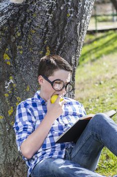 Young boy reading a book in the woods with shallow depth of field and copy space