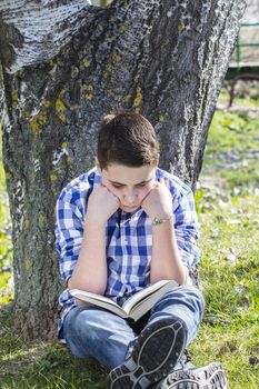 Young boy reading a book in the woods with shallow depth of field and copy space