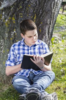 Young boy reading a book in the woods with shallow depth of field and copy space