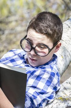 Young boy reading a book in the woods with shallow depth of field and copy space