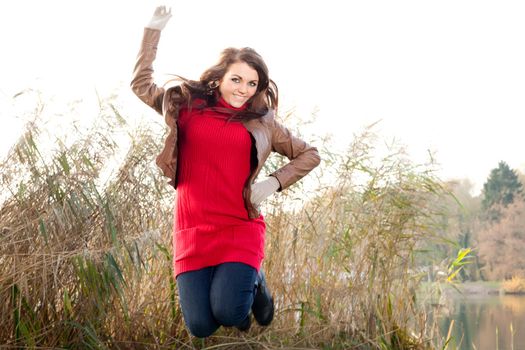 Happy brunette is having a nice time in the park while it's autumn