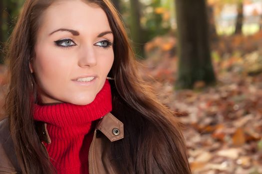 Happy brunette is having a nice time in the park while it's autumn