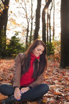 Happy brunette is having a nice time in the park while it's autumn