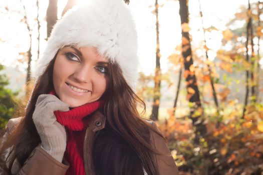 Happy brunette is having a nice time in the park while it's autumn