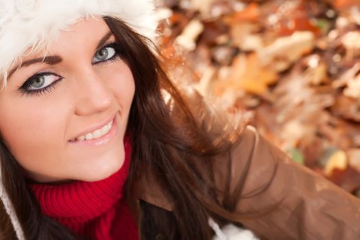 Happy brunette is having a nice time in the park while it's autumn