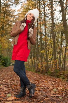 Happy brunette is having a nice time in the park while it's autumn