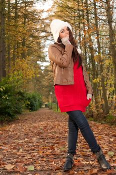 Happy brunette is having a nice time in the park while it's autumn