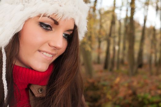 Happy brunette is having a nice time in the park while it's autumn