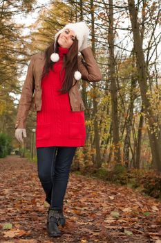 Happy brunette is having a nice time in the park while it's autumn