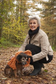 Middle aged woman in the autumn forest with her dog