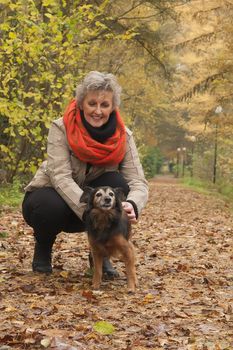 Middle aged woman in the autumn forest with her dog