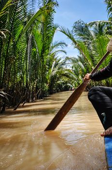A woman with palm leaf conical hat rowing at Tra Su Natural Reserve in Mekong Delta, An Giang, Vietnam
