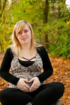 Blond young girl is waiting for her little child. Shoot in the forest