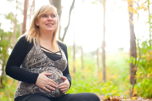 Blond young girl is waiting for her little child. Shoot in the forest