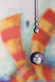 A Macro water drop with the reflection of a snowman, making it look like a snow globe.