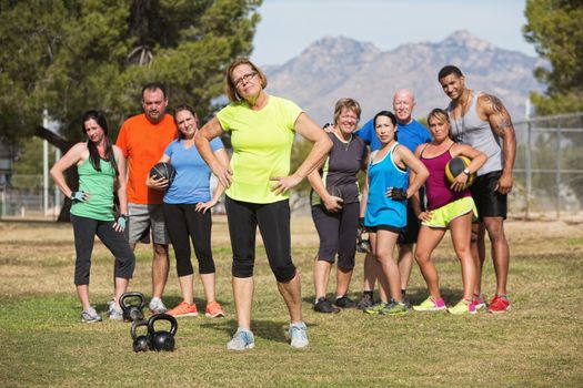 Serious mature woman with boot camp fitness class outdoors