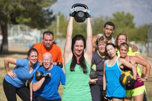 Group of people watching woman lifting kettle bell weights