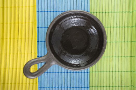 Mexican Oaxaca pottery bowl brown color on tablecloth made of wooden branches.