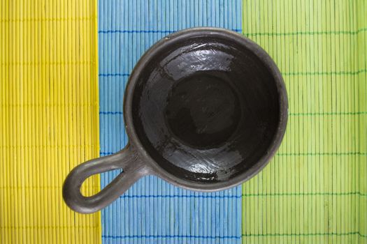 Mexican Oaxaca pottery bowl brown color on tablecloth made of wooden branches.